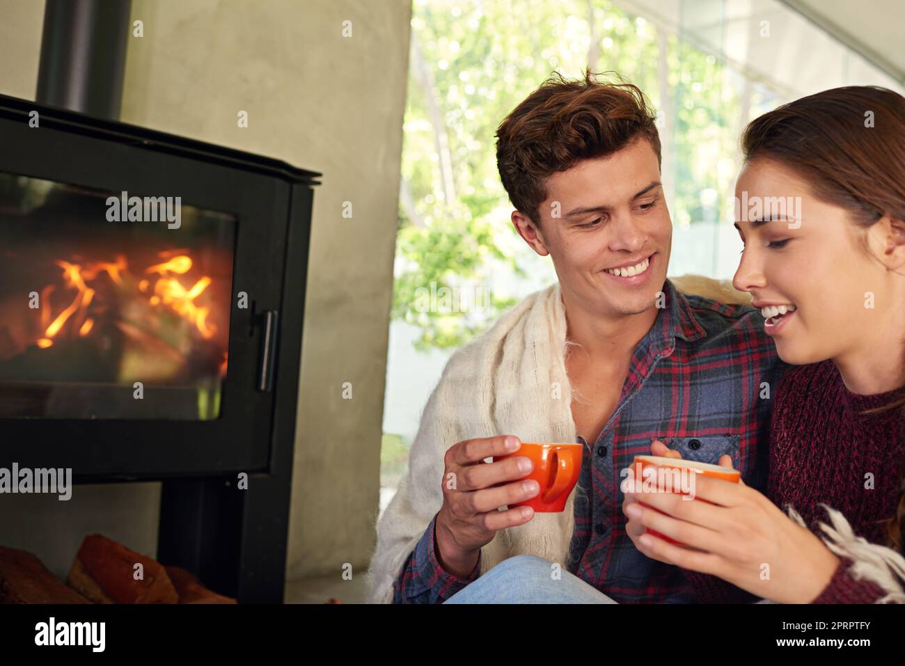 You are my warmth when I feel cold. a young couple drinking hot chocolate by the fireplace. Stock Photo