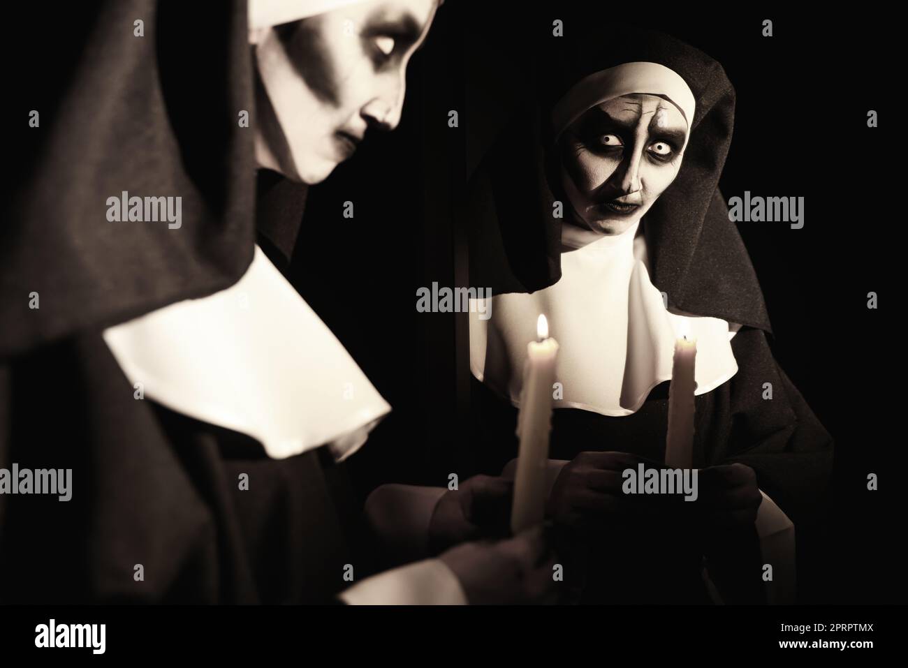 Scary devilish nun with burning candle on black background