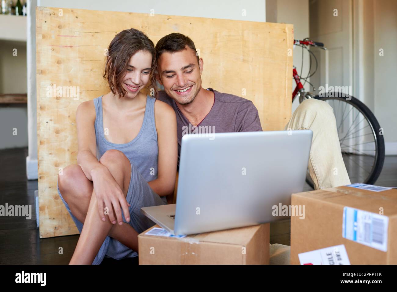Giving the courier company a five-star rating on moving day. an affectionate young couple using a laptop on the floor at home. Stock Photo