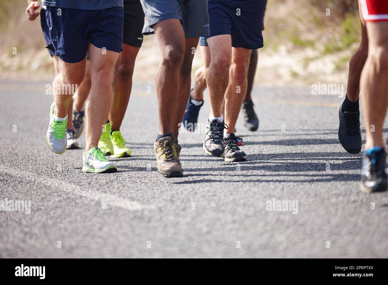 No pain, no gain. Work those legs. the legs of a group of men running a road race. Stock Photo
