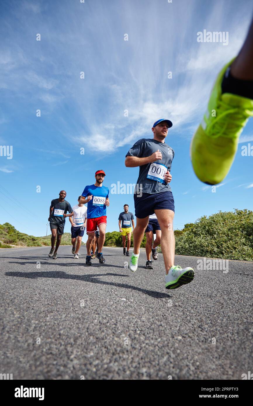 Race for it. Low angle shot of a group of young men running a marathon. Stock Photo