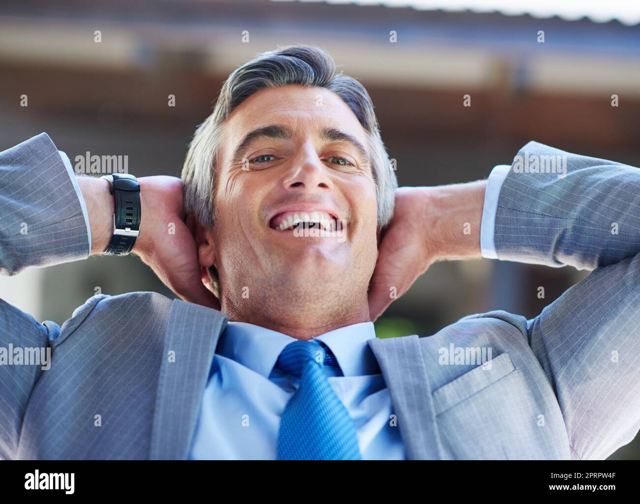 On top of the business world. a content businessman leaning back in his chair with his hands behind his head. Stock Photo