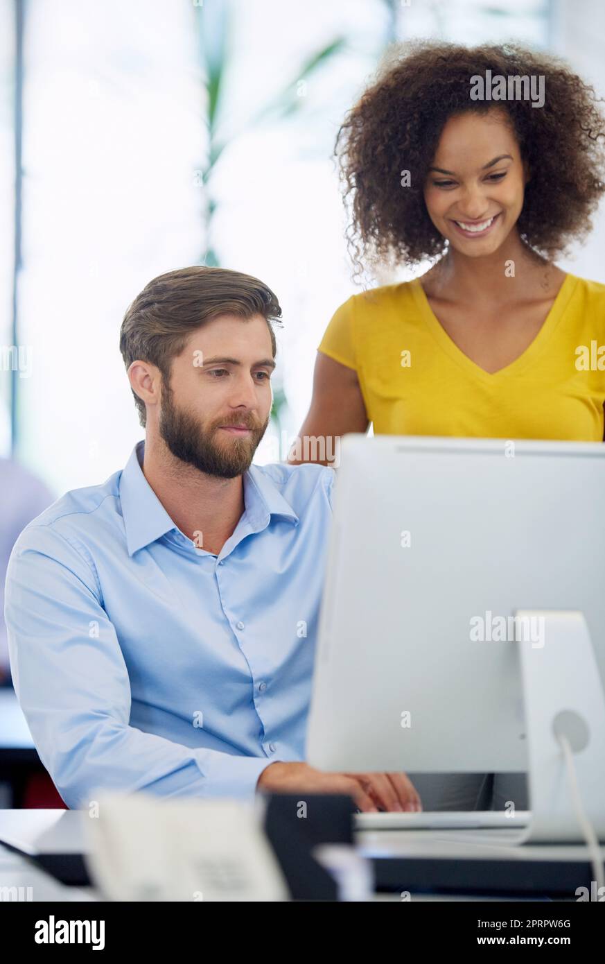 Combining their expertise. two young colleagues working together at a computer. Stock Photo