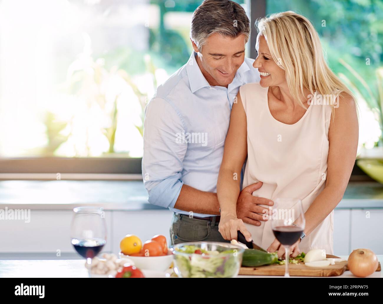 What you making. an affectionate mature couple cooking dinner together in the kitchen. Stock Photo