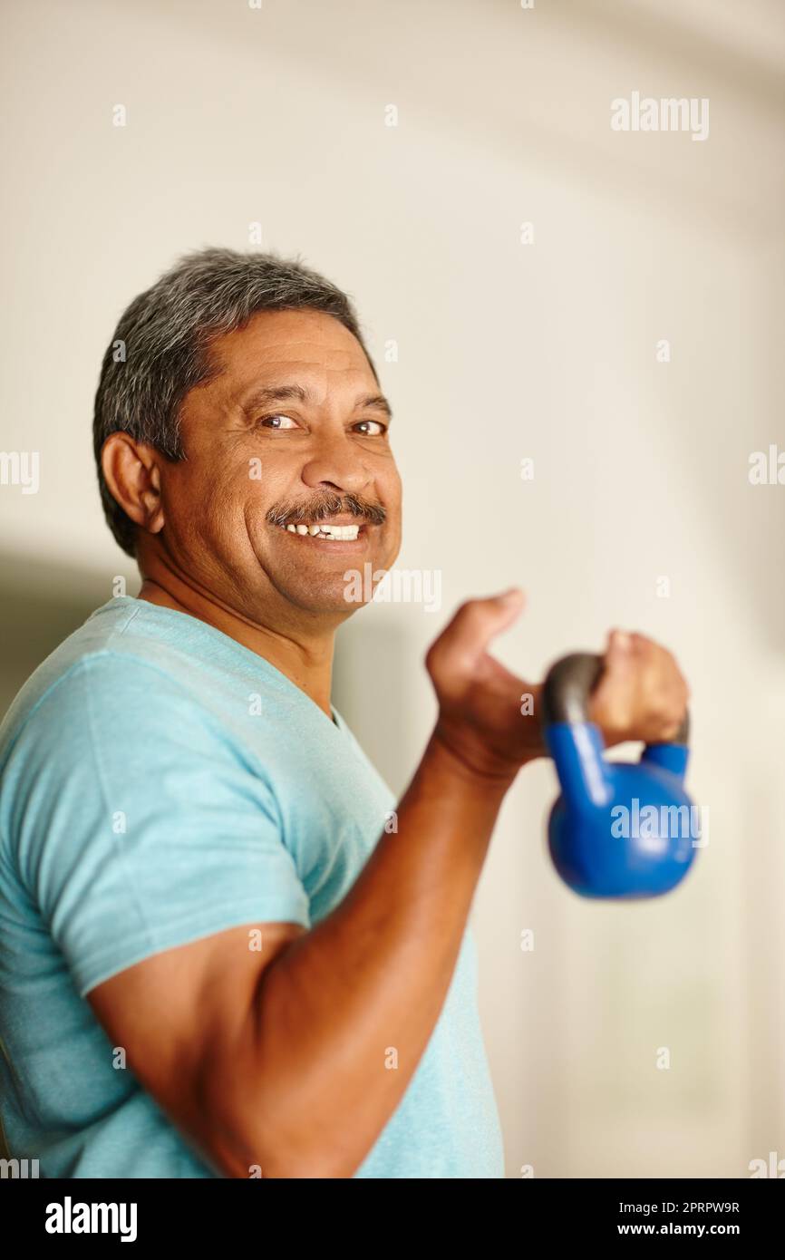 Working those biceps. a mature man lifting dumbbells. Stock Photo