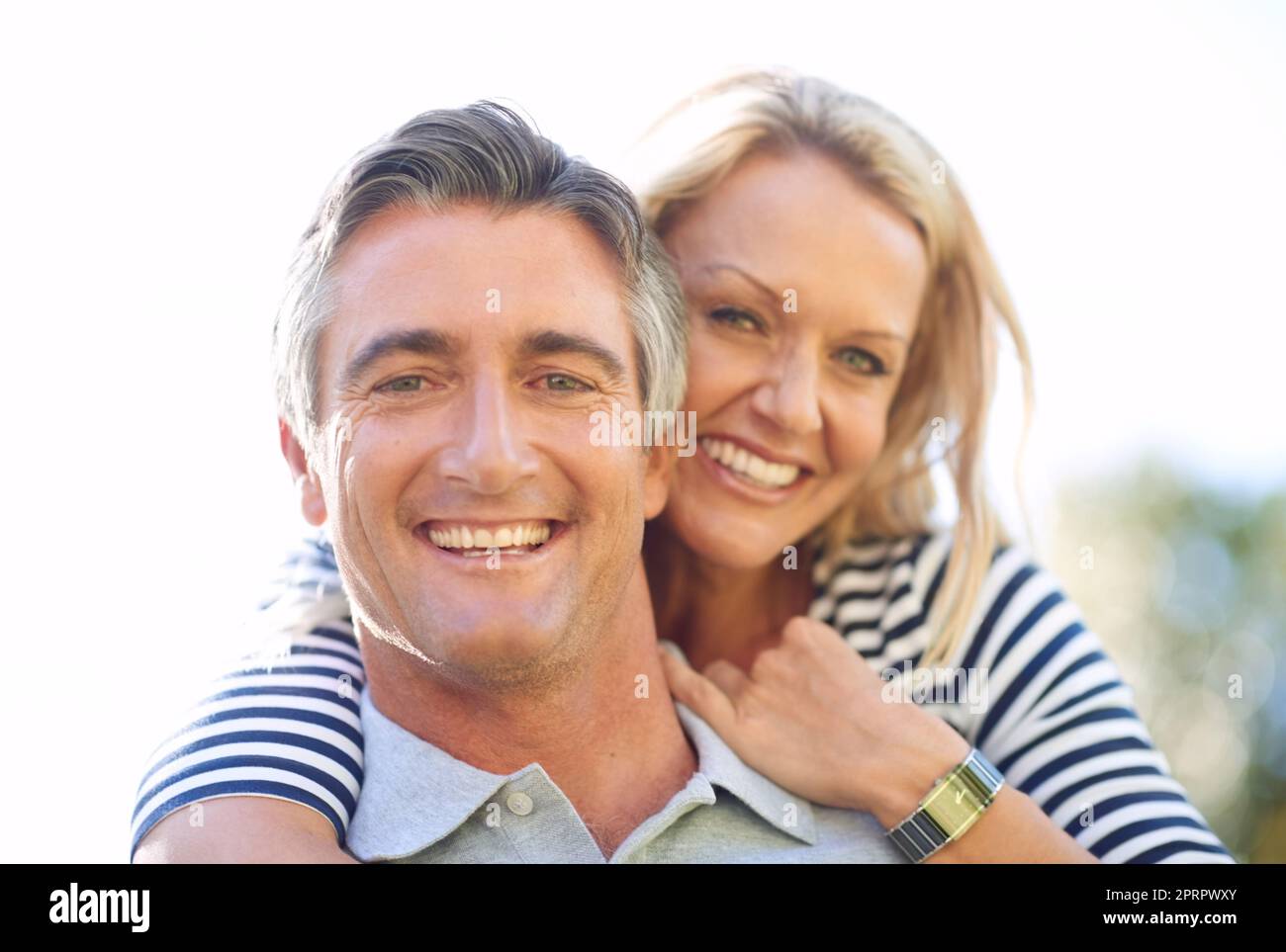 Shes my partner in play. Cropped portrait of a handsome mature man piggybacking his wife in the park. Stock Photo