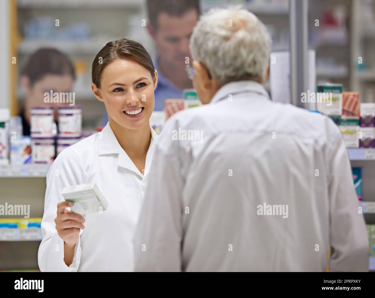 Offering friendly advice to clients. a young pharmacist helping an elderly customer. Stock Photo