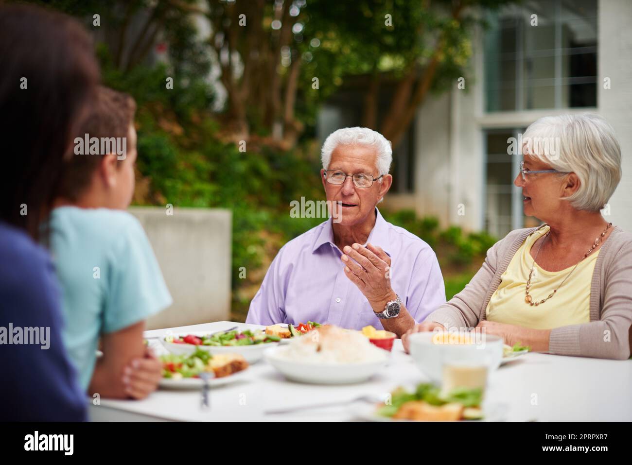Passing on wisdom. a happy multi-generational family having a meal together outside. Stock Photo
