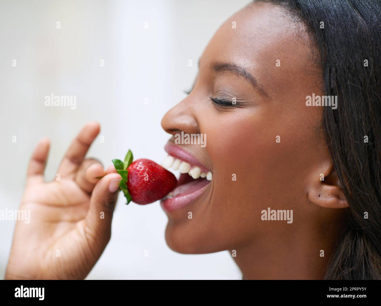Its worth every bite. a beautiful young woman eating strawberries. Stock Photo