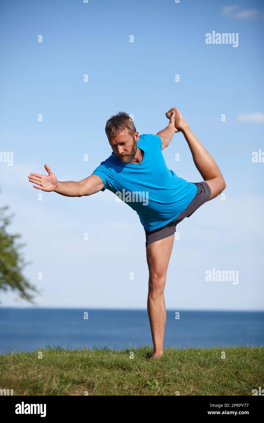 Hes always been a flexible guy. Full length shot of a handsome mature man doing yoga outdoors. Stock Photo