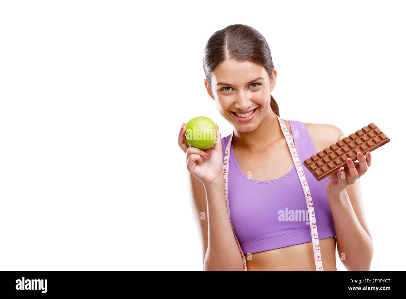 You cant achieve any goals without dicipline. a fit young woman holding an apple in one hand and chocolate in the other. Stock Photo