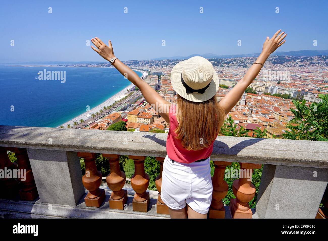 Tourism in French Riviera. Traveler girl with open arms enjoying cityscape of Nice, France. Stock Photo