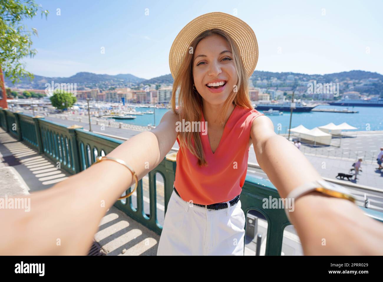 Joyful traveler girl takes self portrait in Nice old port, France Stock Photo