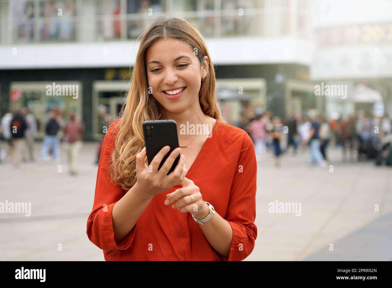 Portrait of smiling young woman using a smartphone app in Berlin, Germany Stock Photo