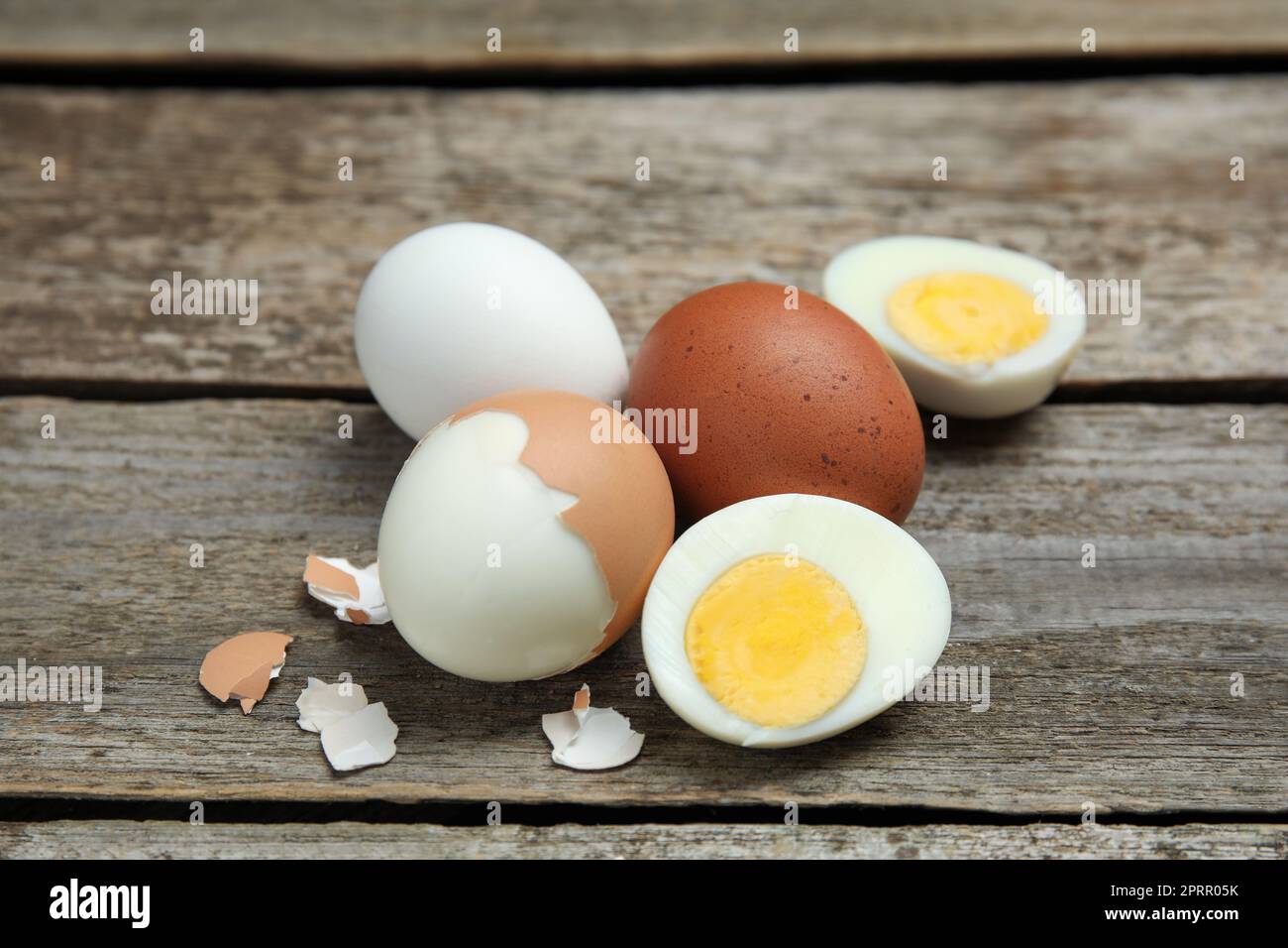 Hard boiled eggs and pieces of shell on wooden table Stock Photo
