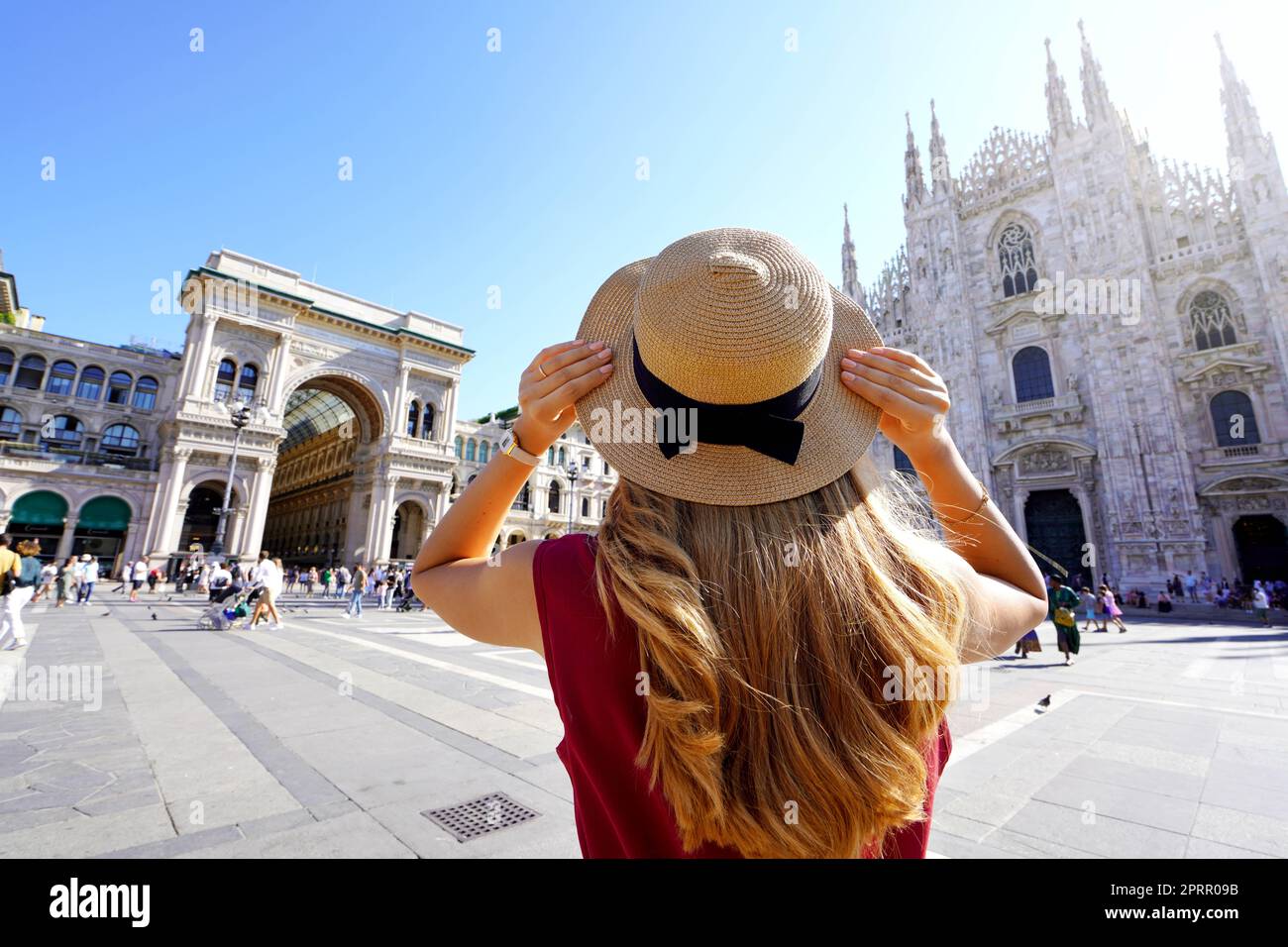 Holidays in Italy. Rear view of traveler girl holds hat in Milan Cathedral Square, Italy. Stock Photo