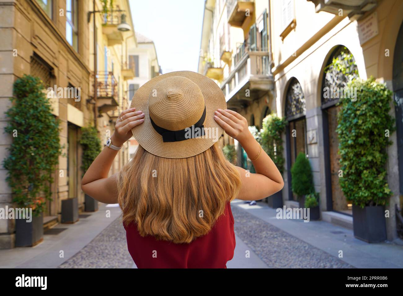 Fashion girl discovering Milan, Italy. Back view of stylish young woman holds hat in Brera district, Milan, Italy. Stock Photo