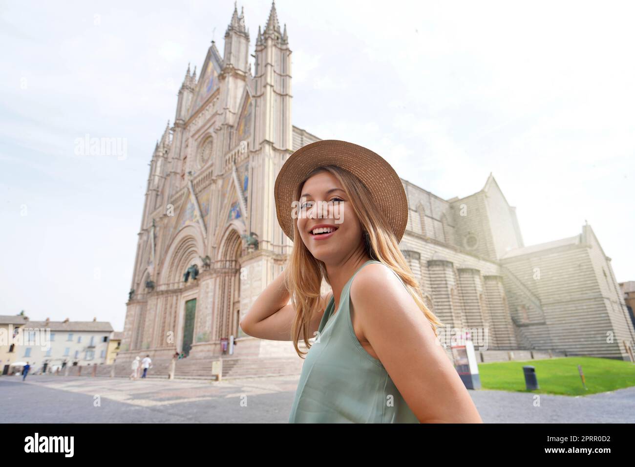 Portrait of young woman walking in Orvieto with the Cathedral on the background, Umbria, Italy Stock Photo