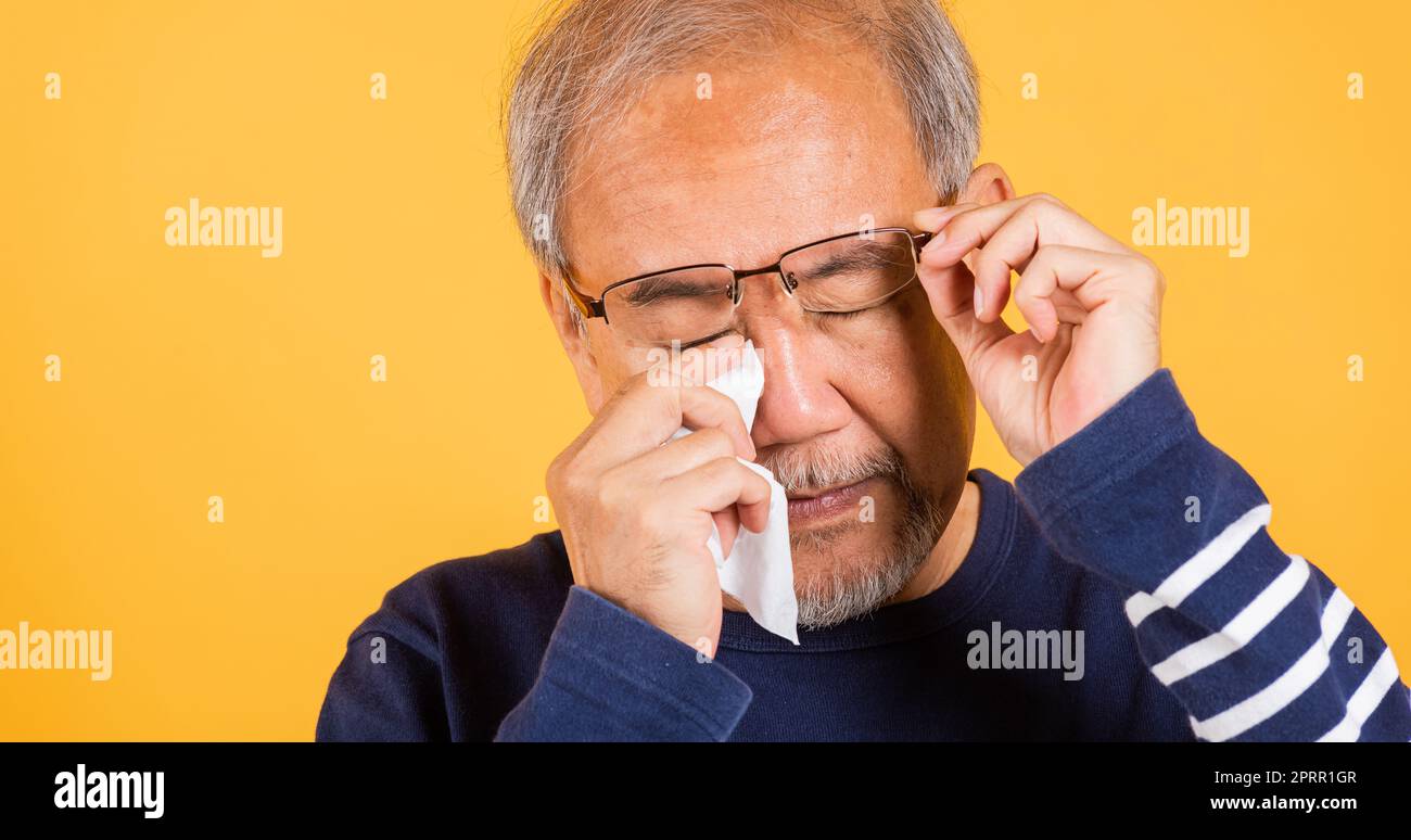Asian elder man crying raise glasses with tissue wipe red eyes Stock Photo