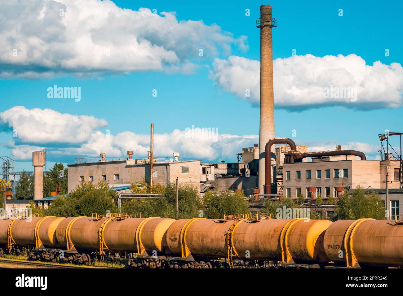 Railway passes through the industrial area with a big plant Stock Photo