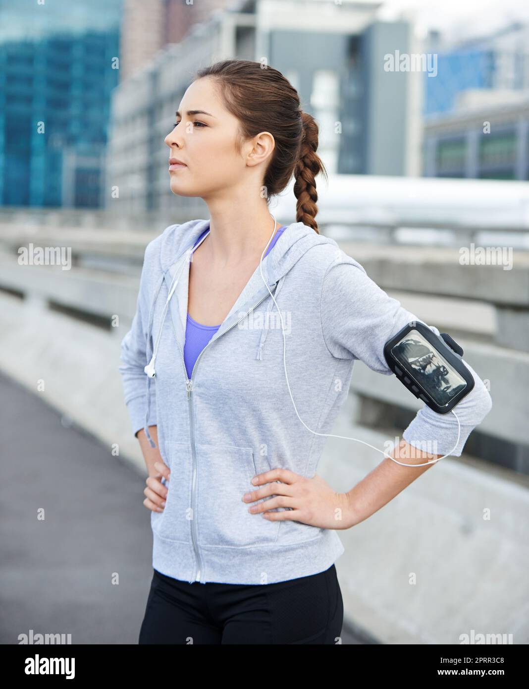 Ready to run to the music. a young female jogger listening to music before a run through the city. Stock Photo