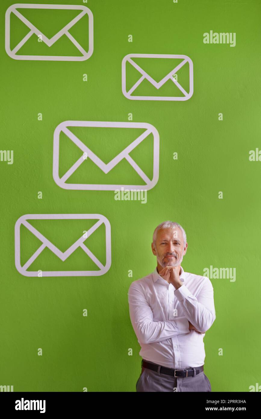 No more snail mail, email. Portrait of a mature businessman standing against a green background filled with message symbols. Stock Photo