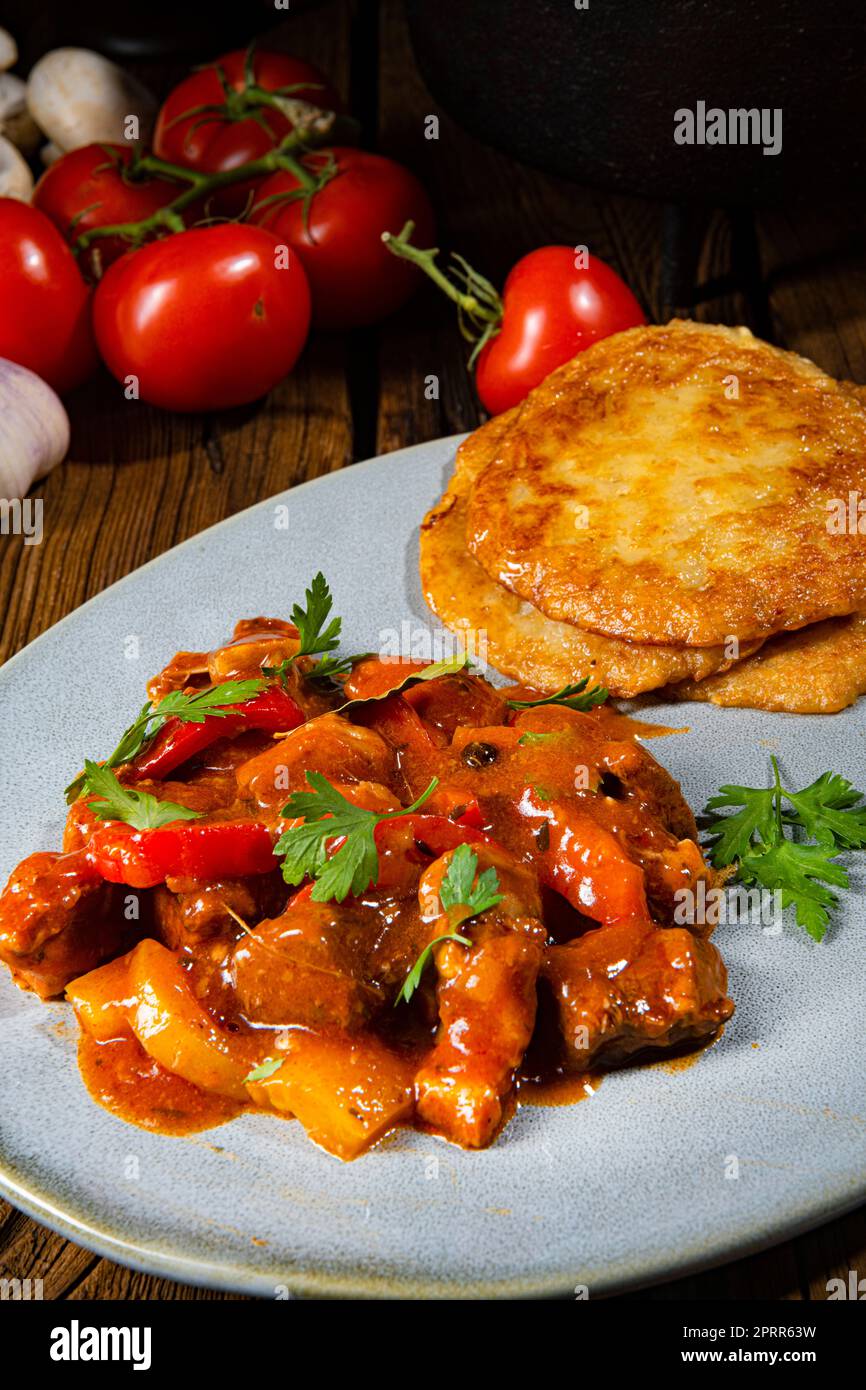 Spicy pork stew with potato pancakes Stock Photo