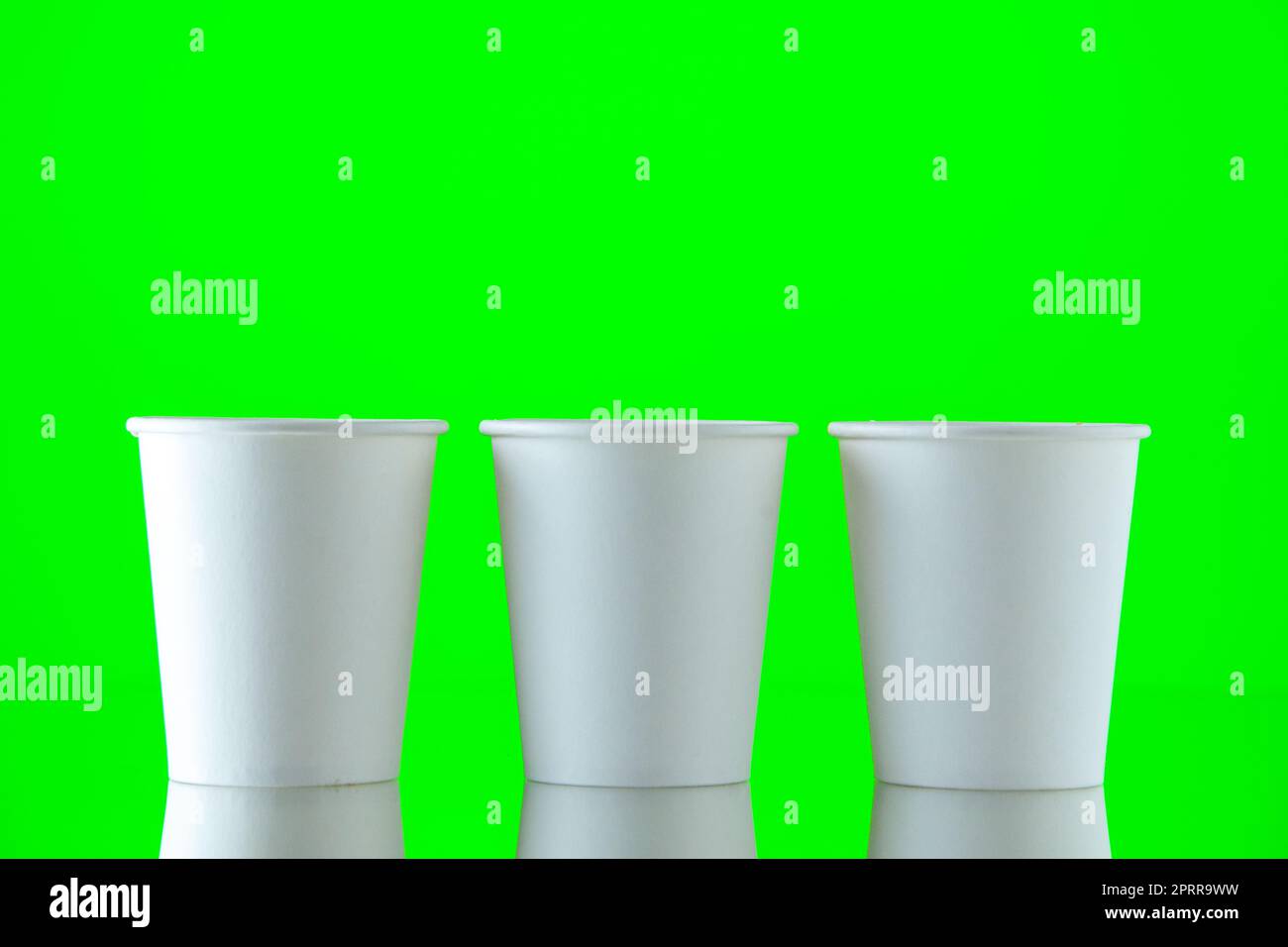 front view paper water cups on neon green background with copy place ...