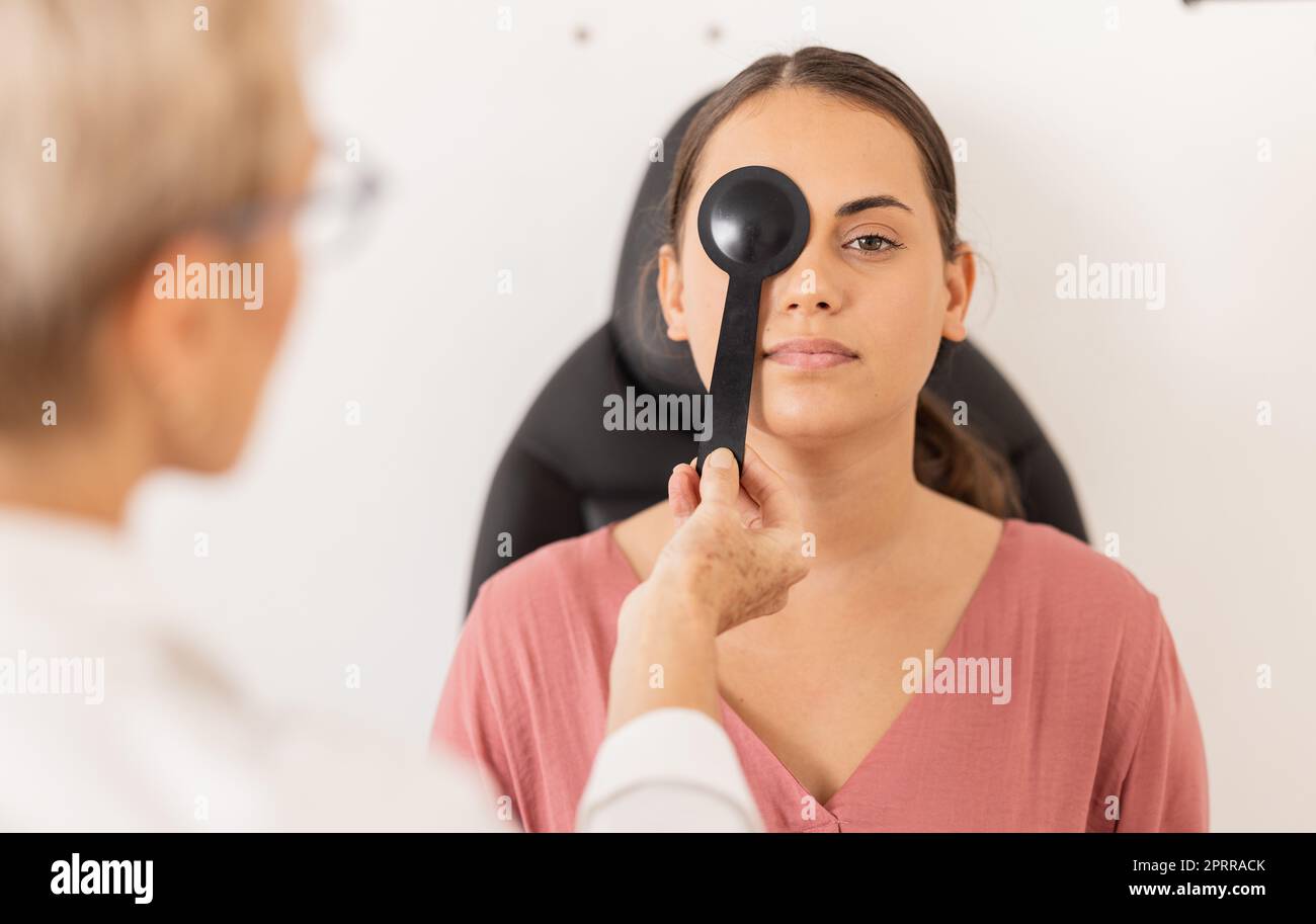 Woman, eye exam and vision test with occluder at optometrist for eyesight, glasses or checkup at
