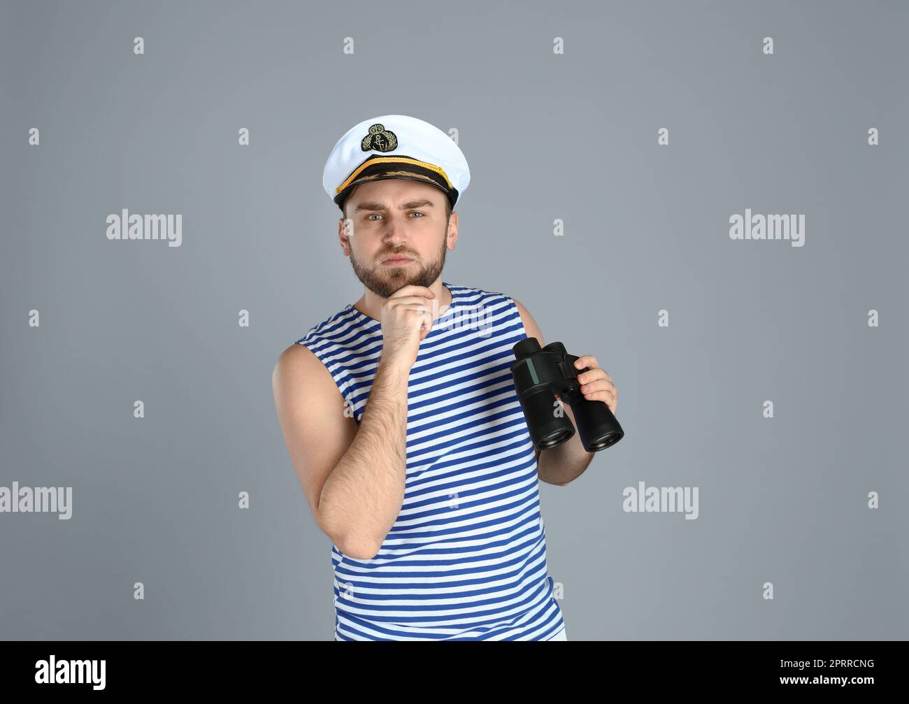 Thoughtful sailor with binoculars on light grey background Stock Photo ...
