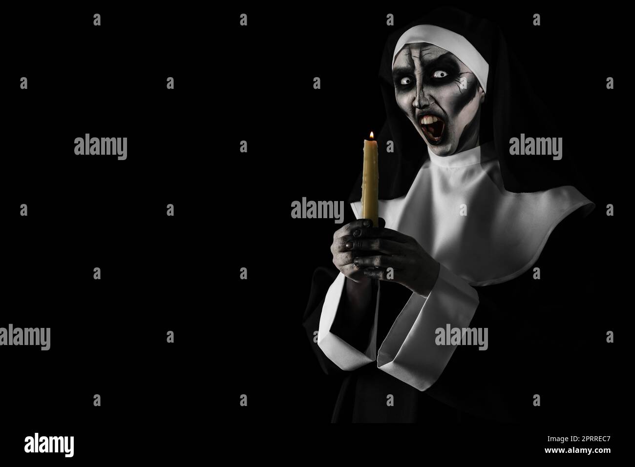 Scary devilish nun with burning candle on black background