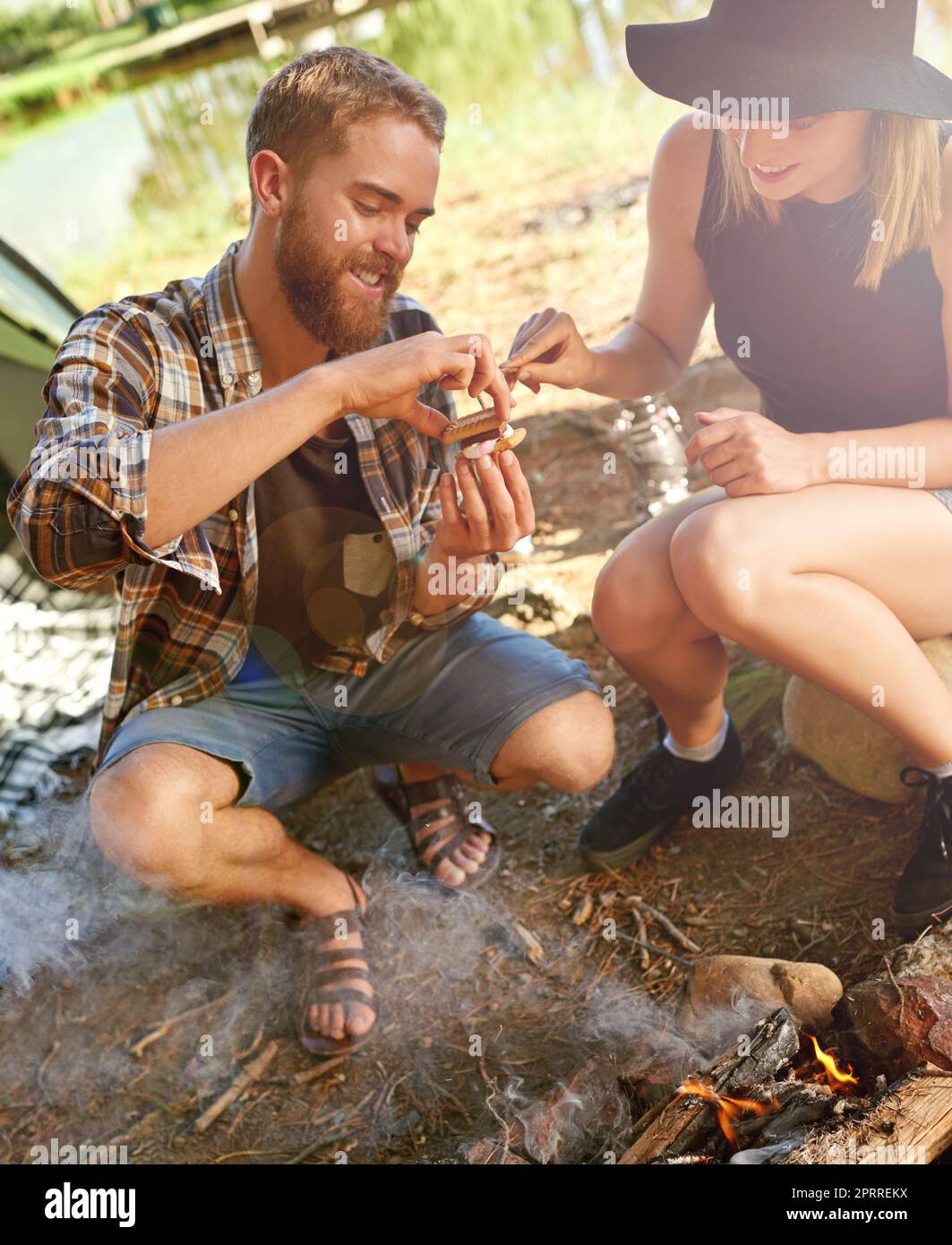 Building the perfect smore. a young couple making smores while camping. Stock Photo