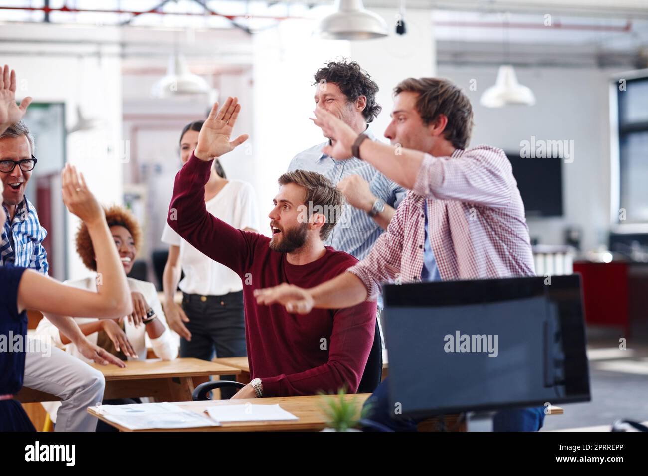 High-fives and happy dances are appropriate in this office. A group of excited designers celebrating a success during an informal office meeting. Stock Photo
