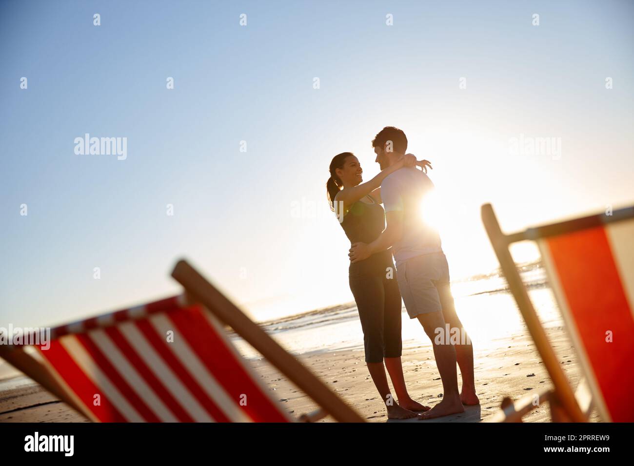 Romantic getaway for fresh romance. a happy young couple on a beach with deck chairs. Stock Photo