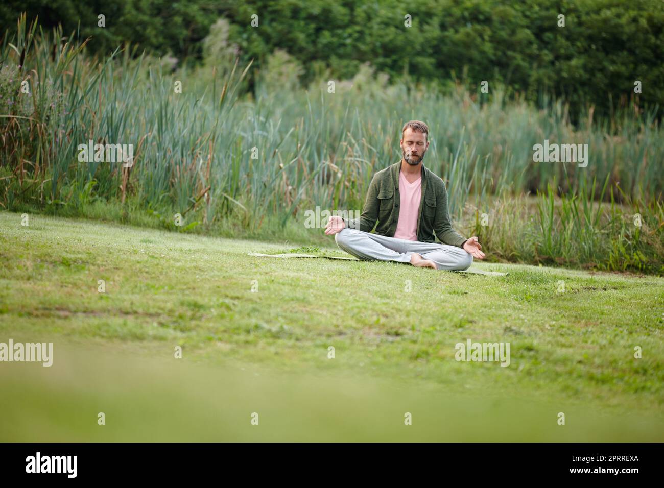 In touch with nature. a handsome mature man meditating in the lotus position in nature. Stock Photo