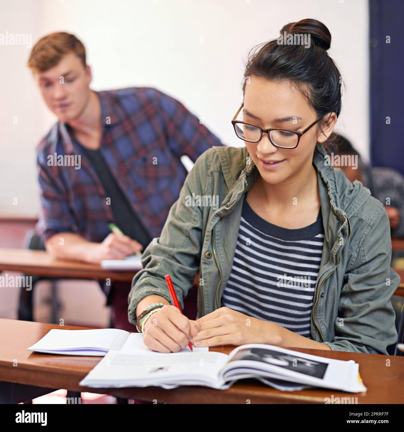 Cheating wont pay off in the end. a student trying to see another students work in class. Stock Photo