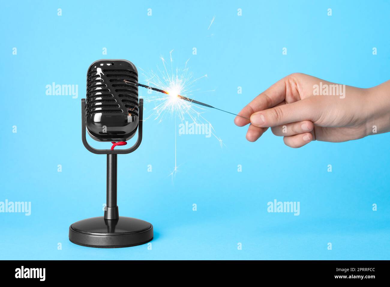 Woman making ASMR sounds with microphone and burning sparkler on light blue  background, closeup Stock Photo - Alamy
