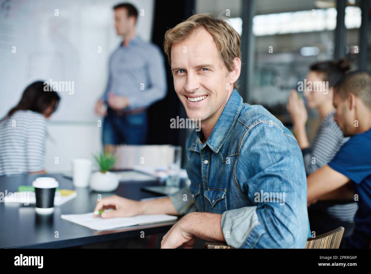 I work with the best colleagues. Portrait of an office worker with his colleagues sitting in the background. Stock Photo
