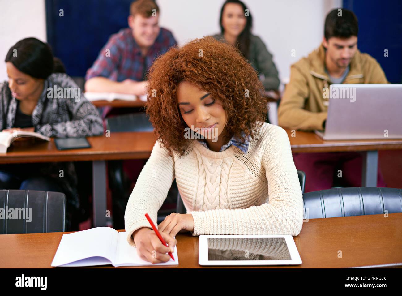 Following my dream. a student working at her desk in class with a digital tablet. Stock Photo