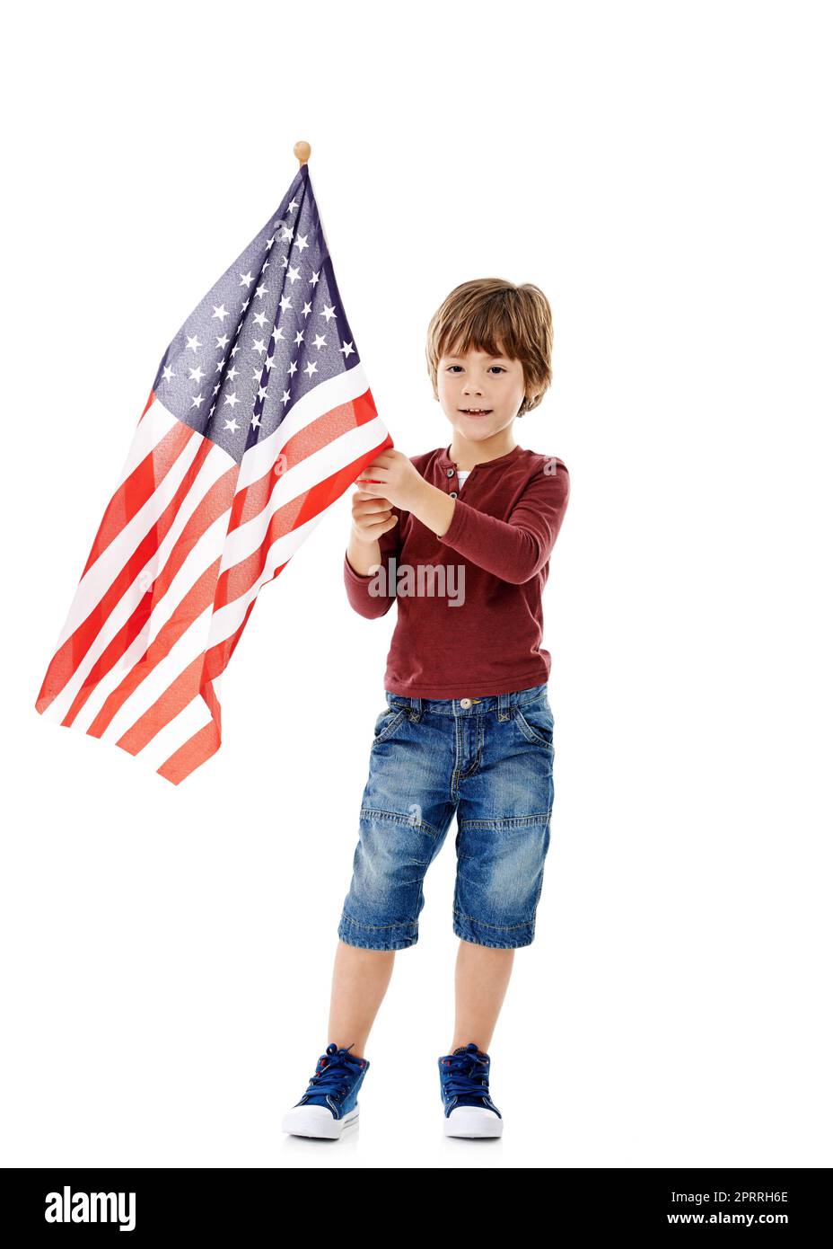 I fly it because Im for it. Studio shot of a cute little boy holding the American flag against a white background. Stock Photo