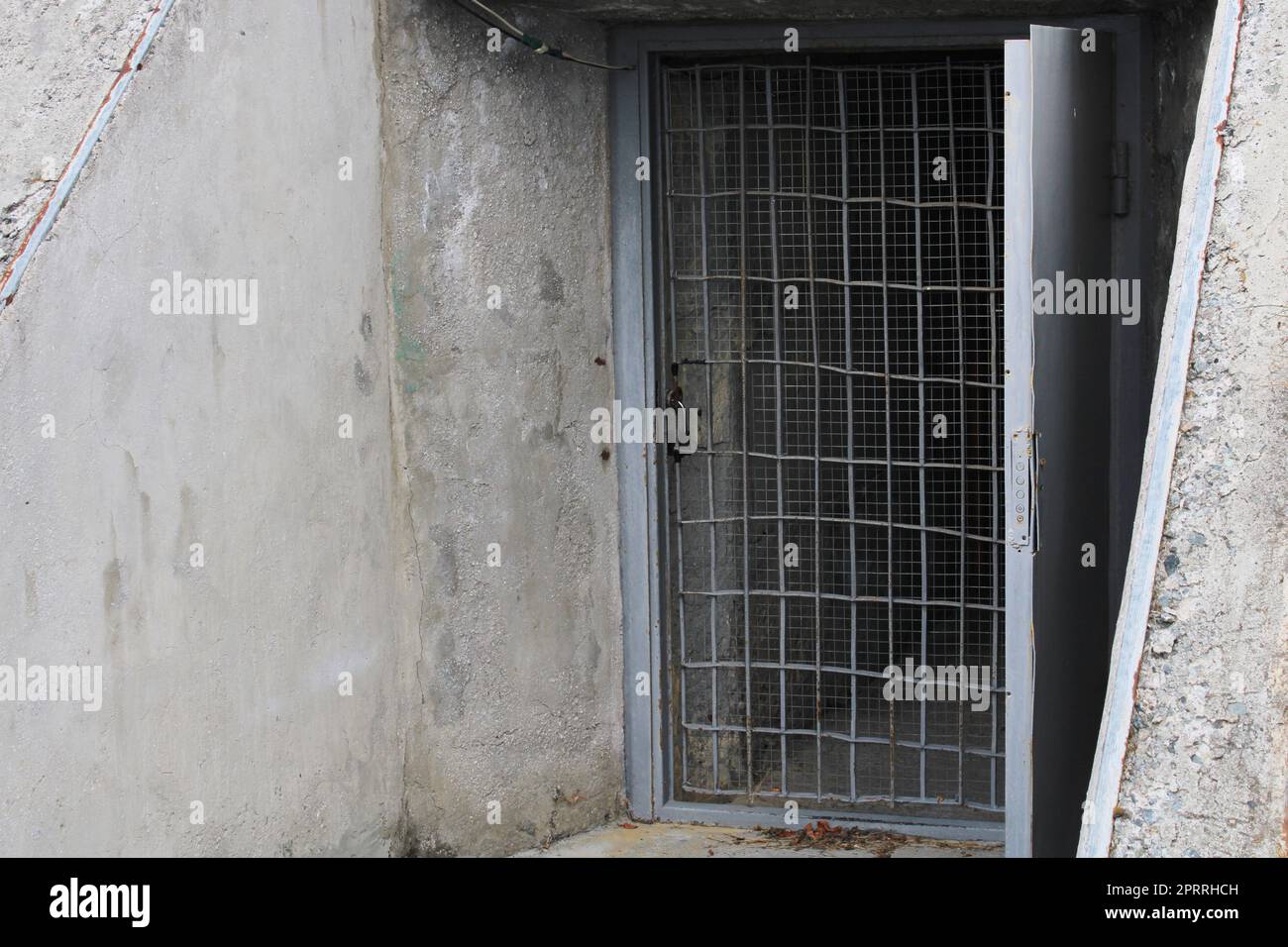 Open door to the cellar with bars in an old stone building Stock Photo