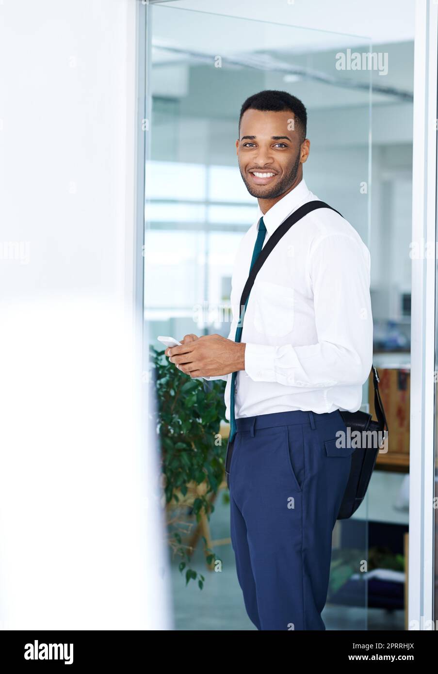 Checking his texts in the office. A handsome young african american businessman using his smartphone while in the office. Stock Photo
