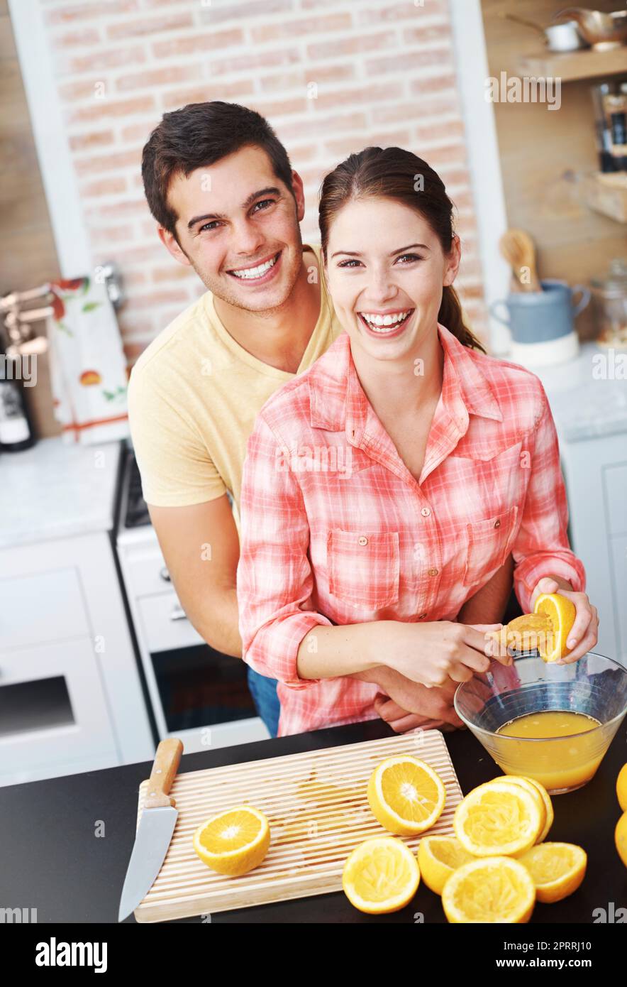 Its the perfect start to any day. A happy young couple making orange juice in their kitchen. Stock Photo