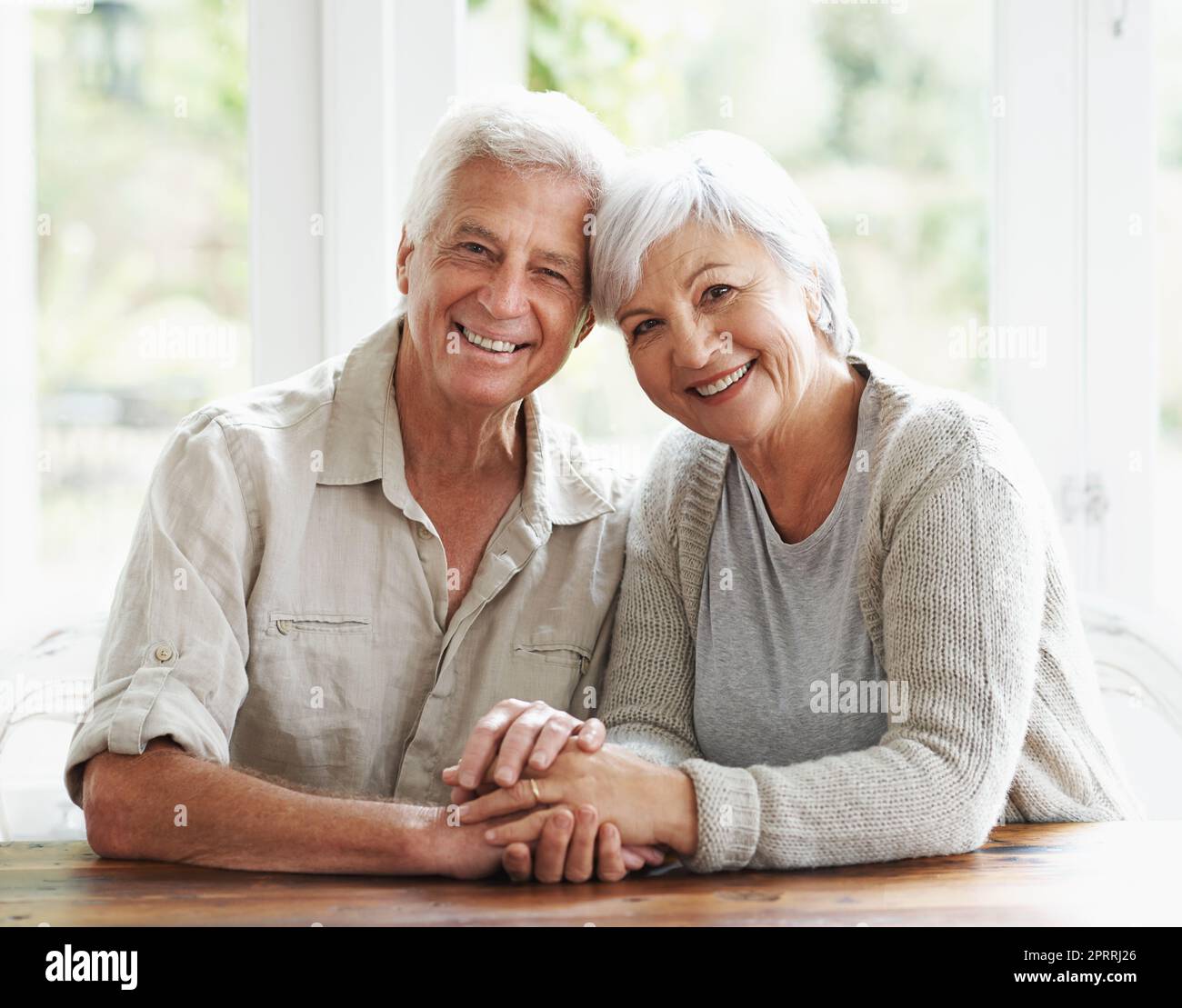 Marriage is easy when youre married to your best friend. A loving senior couple holding hands as they sit at a table. Stock Photo