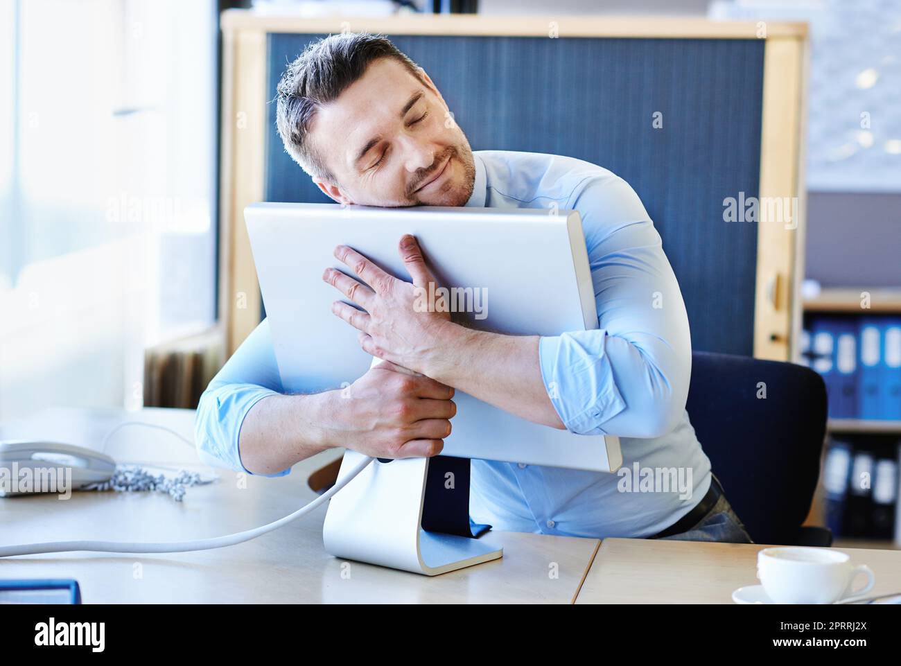 Its a businessmans best friend. a businessman hugging his monitor warmly. Stock Photo