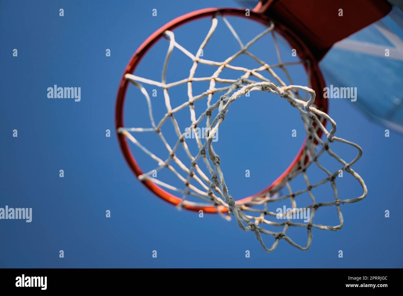 closeup of basketball basket net of white rope view from underneath against a blue sky Stock Photo