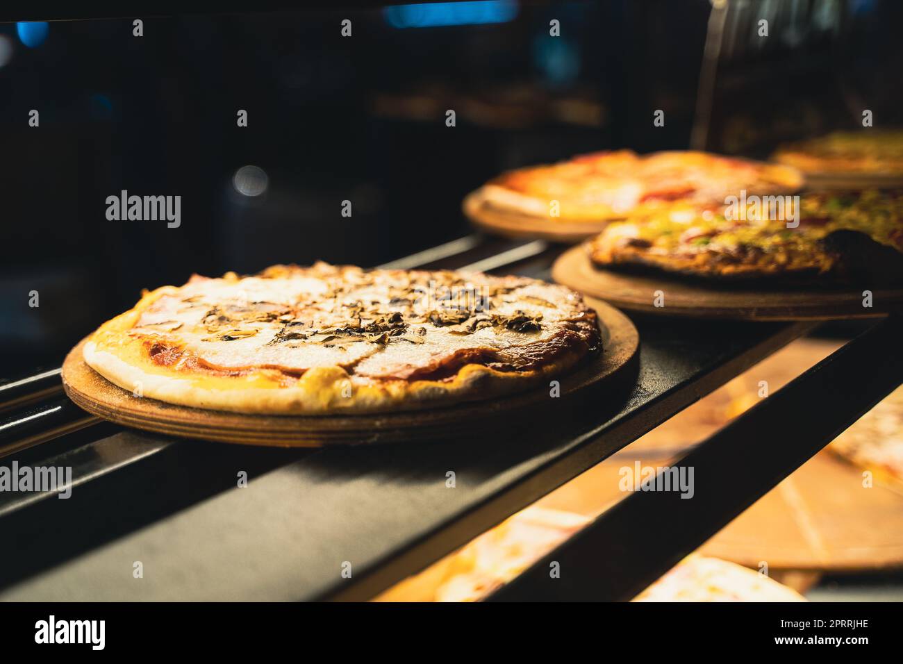 different kinds of pizza on wooden plates on the shelves of street food shop window Stock Photo