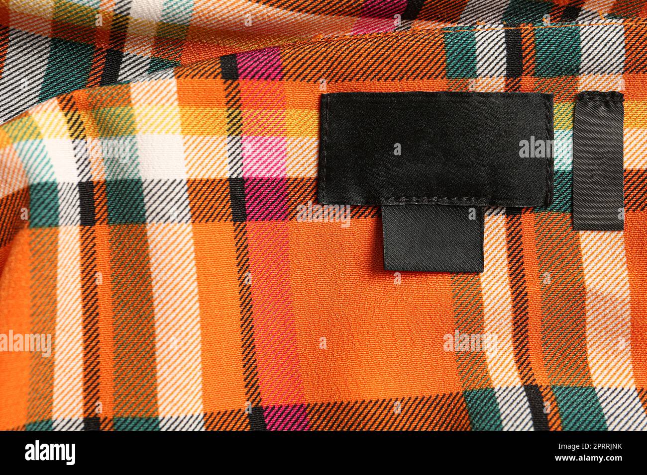 Blank clothing label on checkered apparel, top view. Space for text