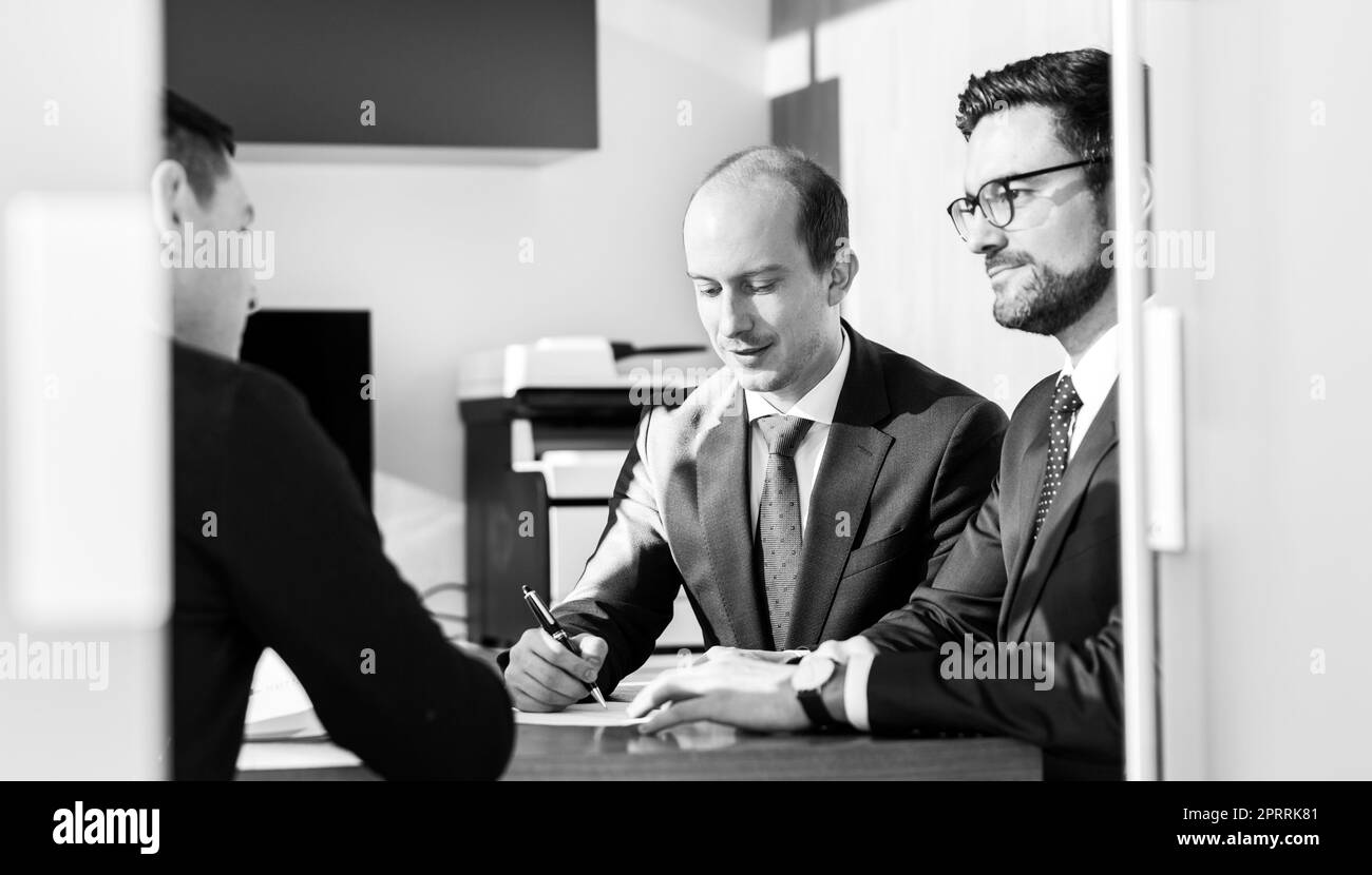 Group of confident successful business people reviewing and signing a contract to seal the deal at business meeting in modern corporate office. Stock Photo