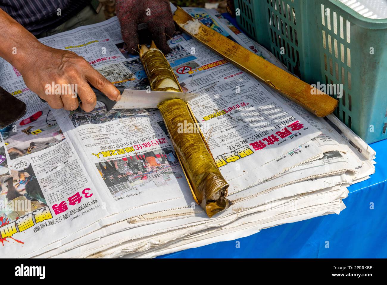 Malaysian man cooking rice in bamboo tube. It is also called Bamboo Rice or Fragrant Bamboo Rice
